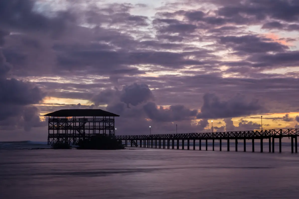 The Cloud 9 boardwalk in General Luna, Siargao, under purple sunrise clouds