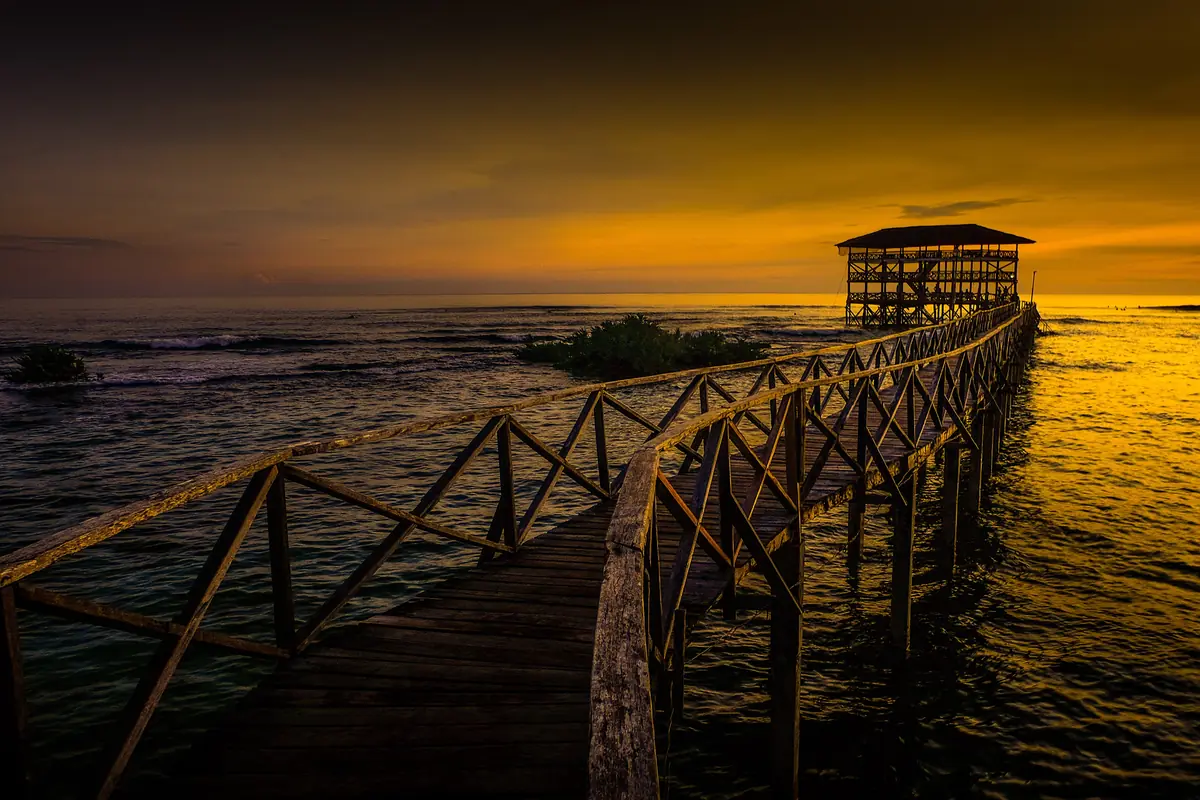 The wooden surf boardwalk at Cloud 9, Siargao, under a golden sunset