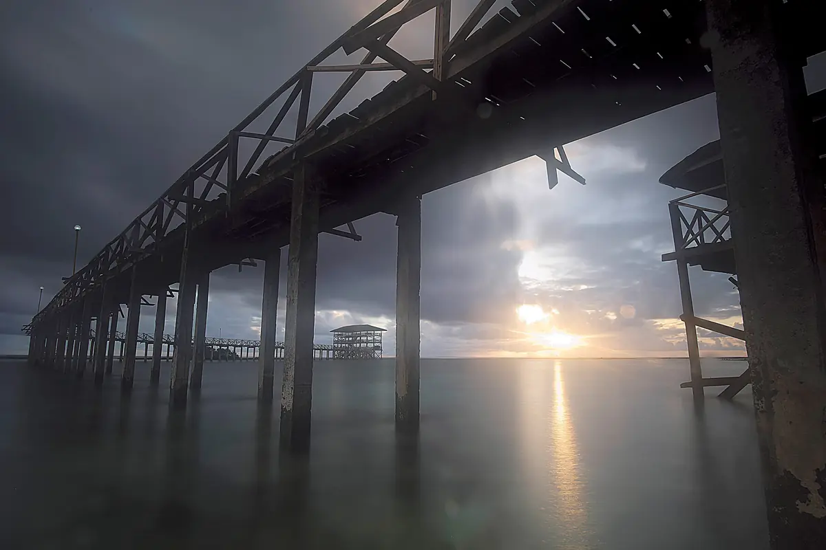Looking out from beneath the Cloud 9 boardwalk as the sun sets over the sea